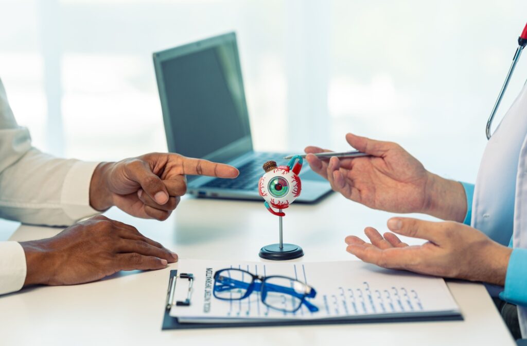 A close-up of a patient’s hands pointing to a 3D eye model during a discussion with their eye doctor.