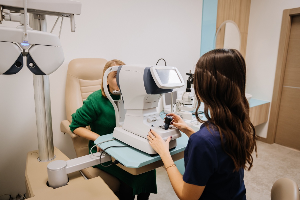 A patient undergoing pre-testing with an autorefractor at Pinehouse Eyecare in Saskatoon. The optometric assistant operates the device to measure vision before the main exam.
