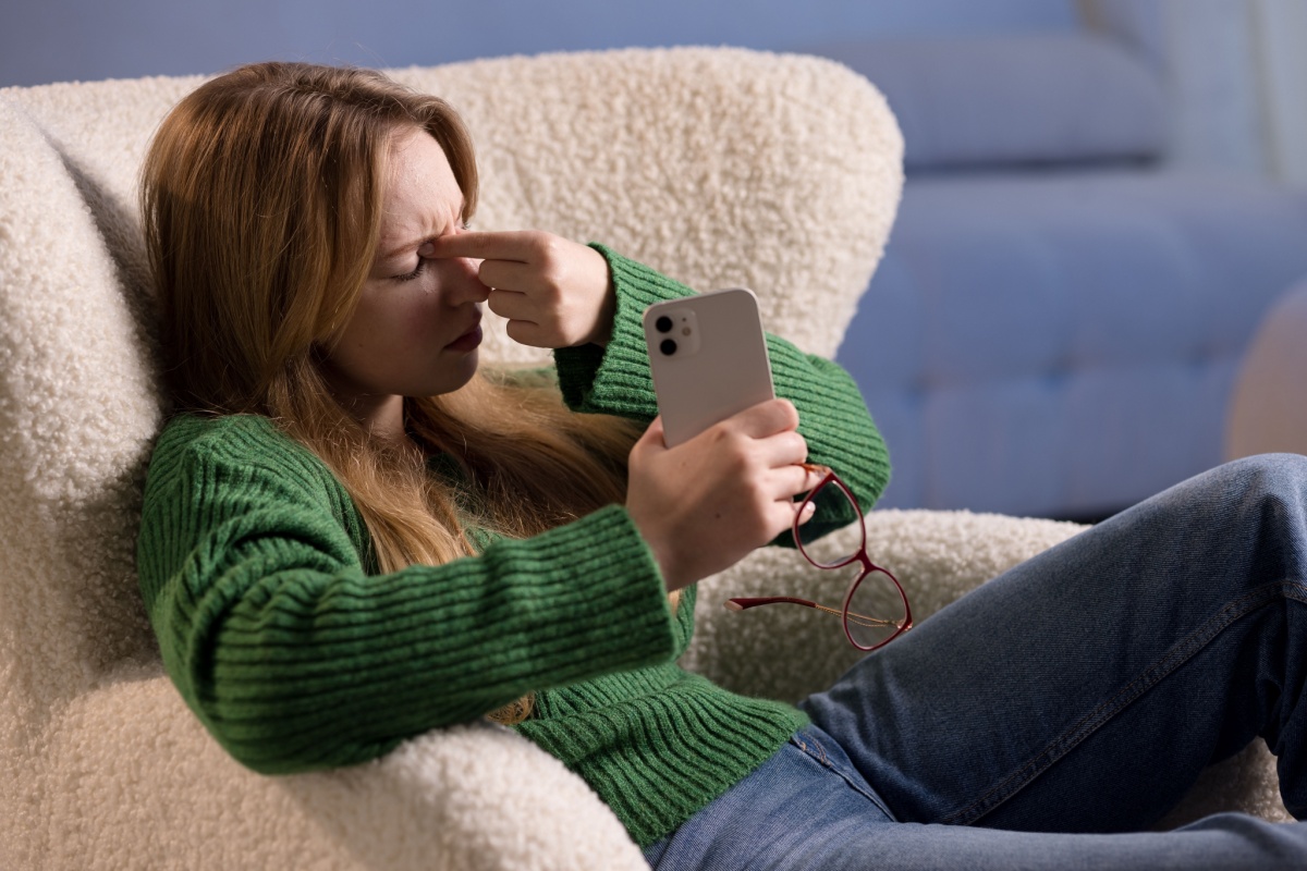Woman holding her glasses and rubbing her eyes.